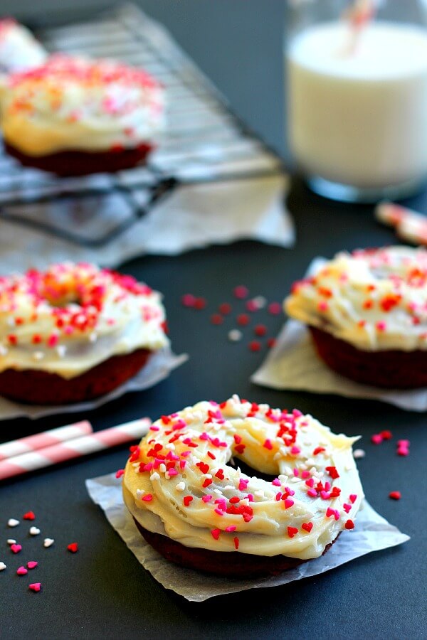 Frosted red velvet cake donuts on separate squares of parchment paper. 