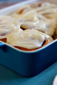 overnight cinnamon rolls with cream cheese frosting in a blue dish