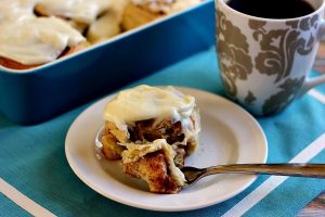 cinnamon roll on a white dish with a fork