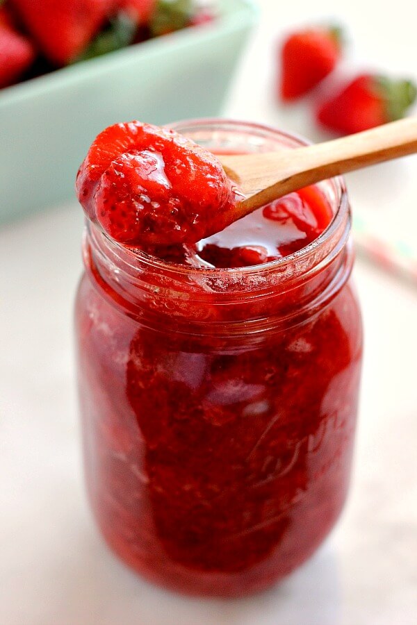 jar of strawberry topping with a small wooden spoon