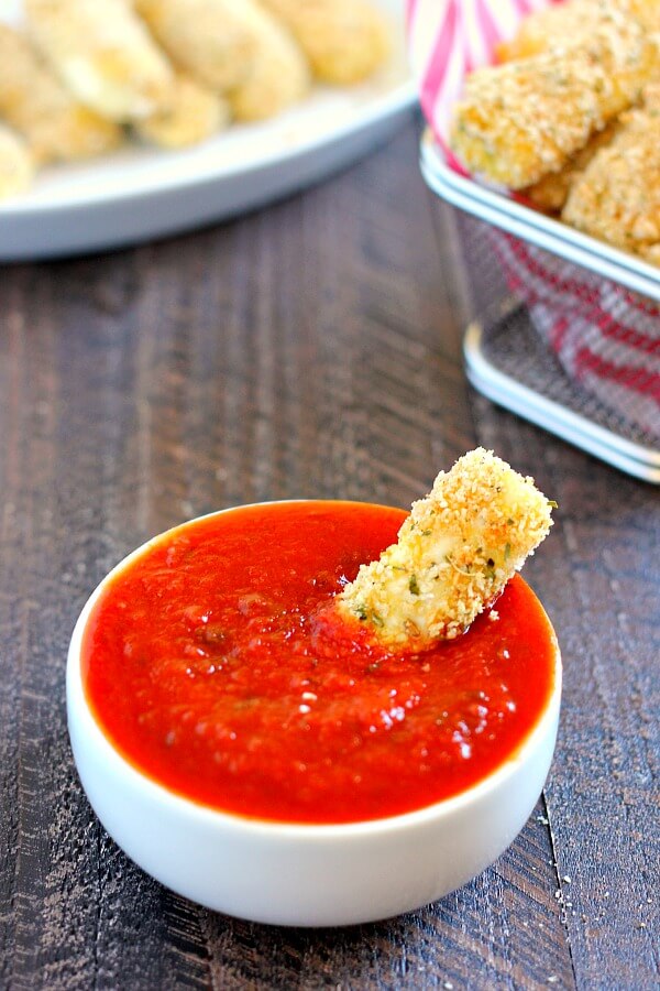 single homemade mozzarella stick dipped in bowl of marinara sauce