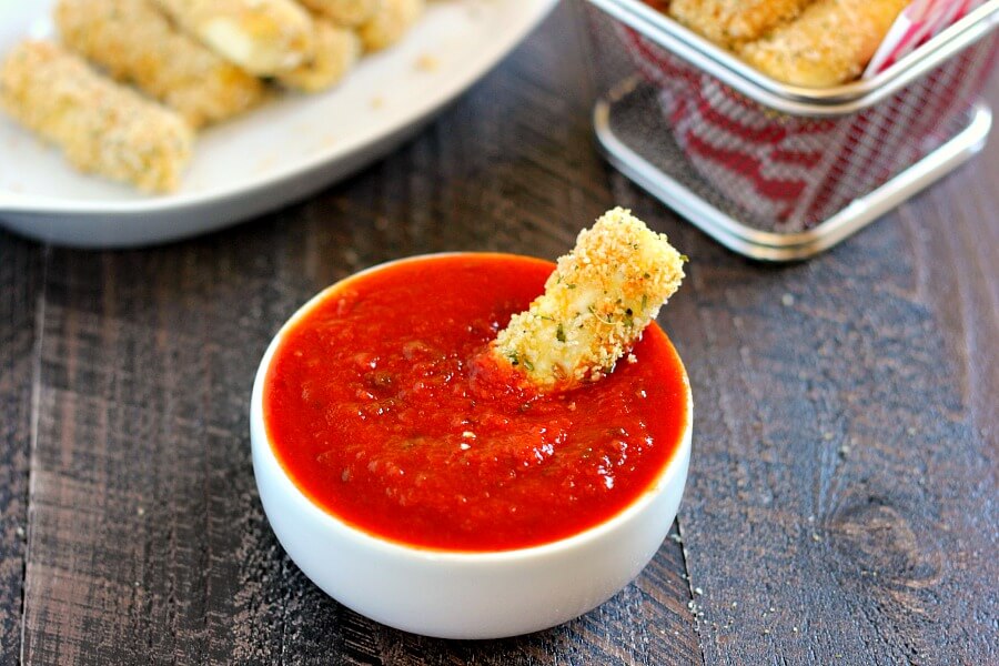 baked mozzarella stick sitting in bowl of marinara sauce