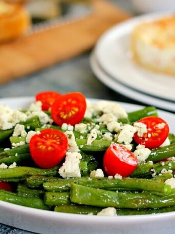 This Roasted Garlic Green Bean Salad is filled with fresh beans, ripe tomatoes and feta cheese, combined with a light garlic and lemon dressing!