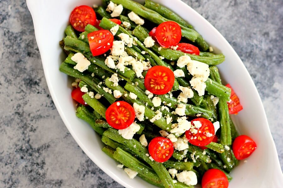Roasted Garlic Green Beans are filled with fresh beans, ripe tomatoes and feta cheese, combined with a light garlic and lemon dressing! #greenbeans #greenbeanrecipe #roastedgreenbeans #vegetables #roastedvegetables #sidedish #easysidedish
