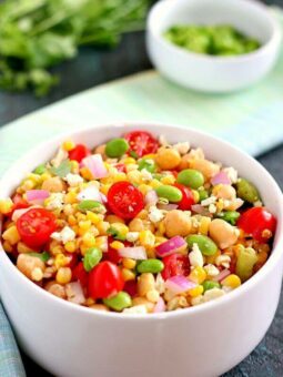 Jam-packed with corn, edamame, chickpeas, and tomatoes, this Corn, Edamame, and Chickpea Salad is full of flavor and makes the perfect light lunch or dinner. By adding a touch of feta cheese, red onion, cilantro, lime juice, and a white balsamic dressing, the ingredients blend together to make a zesty dish!