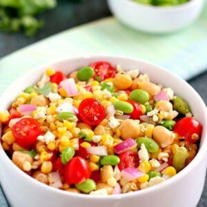 Jam-packed with corn, edamame, chickpeas, and tomatoes, this Corn, Edamame, and Chickpea Salad is full of flavor and makes the perfect light lunch or dinner. By adding a touch of feta cheese, red onion, cilantro, lime juice, and a white balsamic dressing, the ingredients blend together to make a zesty dish!