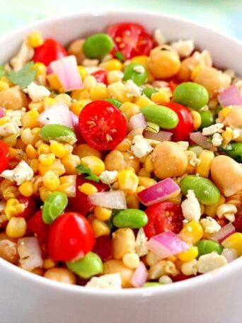 Jam-packed with corn, edamame, chickpeas, and tomatoes, this Corn, Edamame, and Chickpea Salad is full of flavor and makes the perfect light lunch or dinner. By adding a touch of feta cheese, red onion, cilantro, lime juice, and a white balsamic dressing, the ingredients blend together to make a zesty dish!