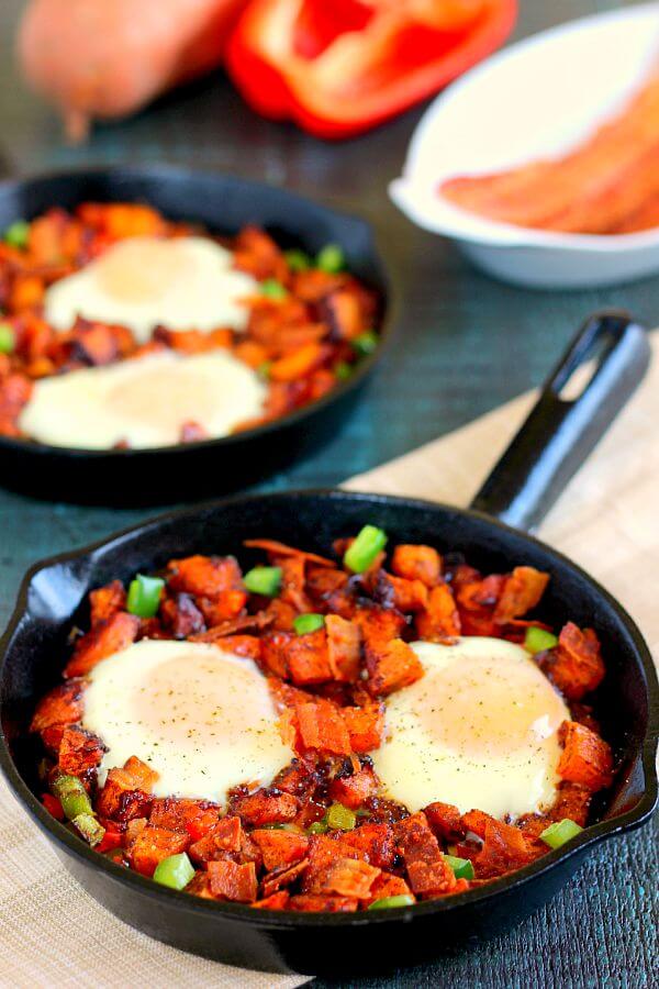 Packed with roasted maple sweet potatoes, fresh eggs, peppers, and bacon, this Roasted Maple Sweet Potato Breakfast Skillet comes together in minutes and makes a hearty breakfast. It's easy to prepare and full of cozy flavors that are perfect on those cool, fall mornings! #sweetpotatoes #roastedsweetpotatoes #sweetpotatorecipes #skillet #breakfastskilletrecipes #breakfastideas #recipe #fallbreakfastideas #fallbreakfastrecipes