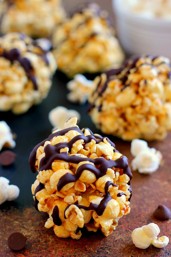 four caramel popcorn balls on a countertop 