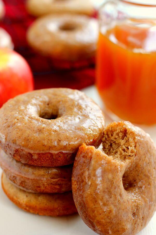 A stack of three baked apple cider donuts with a fourth leaning against the stack. 