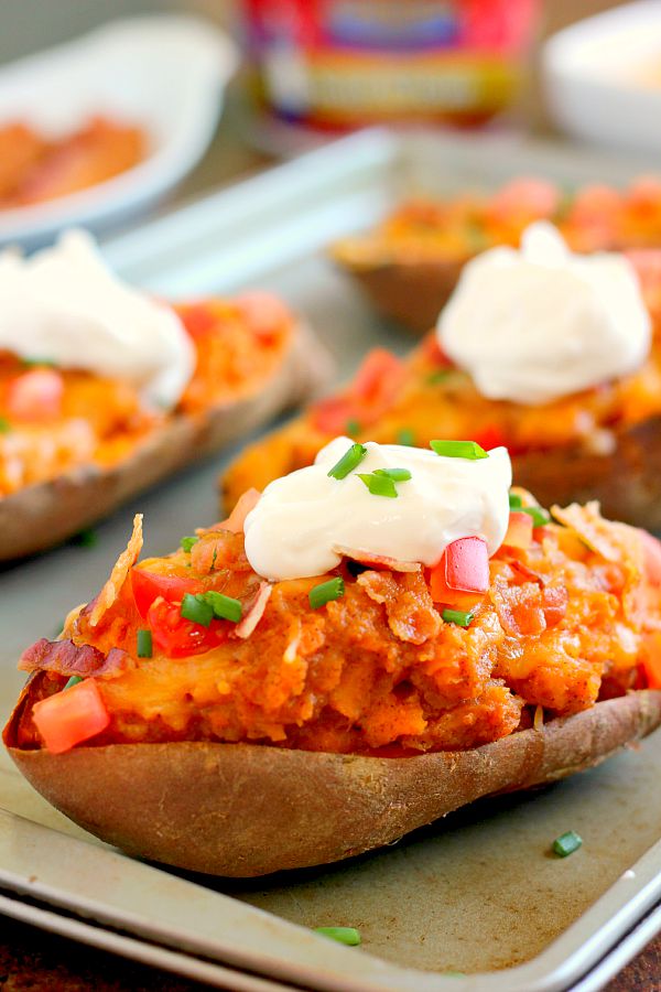 These Loaded Twice Baked Sweet Potatoes make the perfect side dish for any meal. The sweet potatoes are packed with with a brown sugar and cinnamon filling and then topped with cheese, crispy bacon, and sour cream. It's filled with flavor and the perfect fall dish for when you want something warm and comforting! #sweetpotatoes #sweetpotatorecipe #bakedsweetpotatoes #bakedsweetpotatorecipes #potatorecipes #sidedishes #fallrecipes