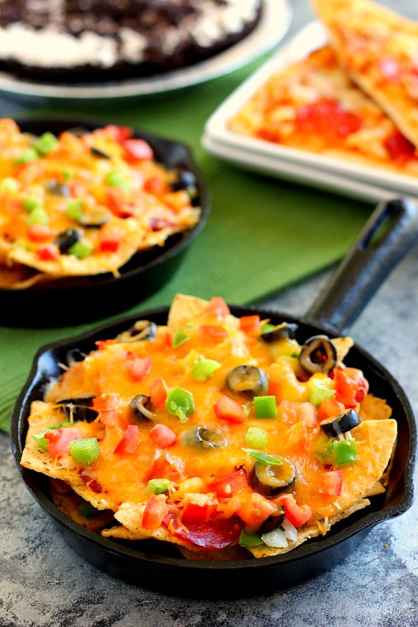 These Pizza Skillet Nachos are packed with two kinds of cheese, hearty pepperoni, black olives, tomatoes, and green peppers. Filled with classic pizza toppings, this is the perfect snack to munch on while relaxing on game day!