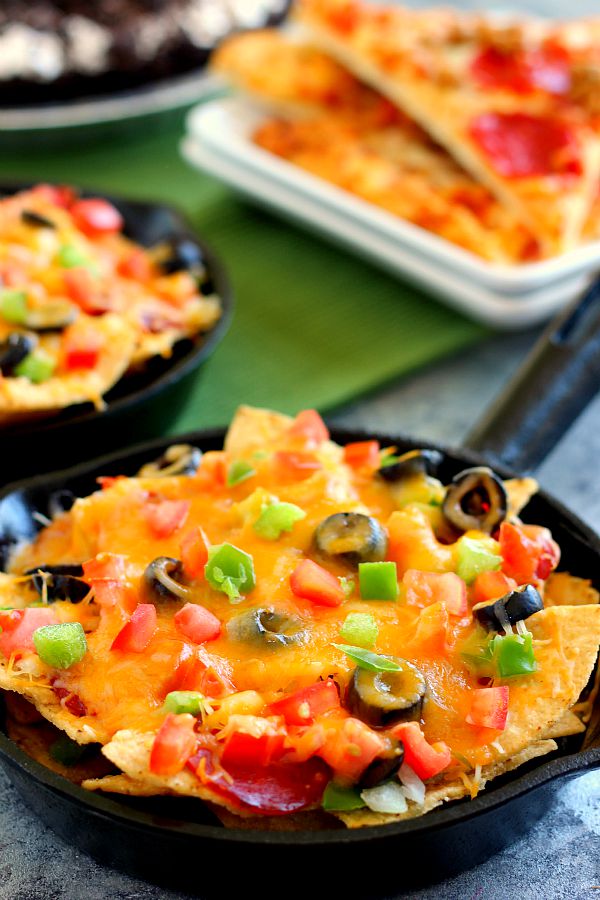 These Pizza Skillet Nachos are packed with two kinds of cheese, hearty pepperoni, black olives, tomatoes, and green peppers. Filled with classic pizza toppings, this is the perfect snack to munch on while relaxing on game day!