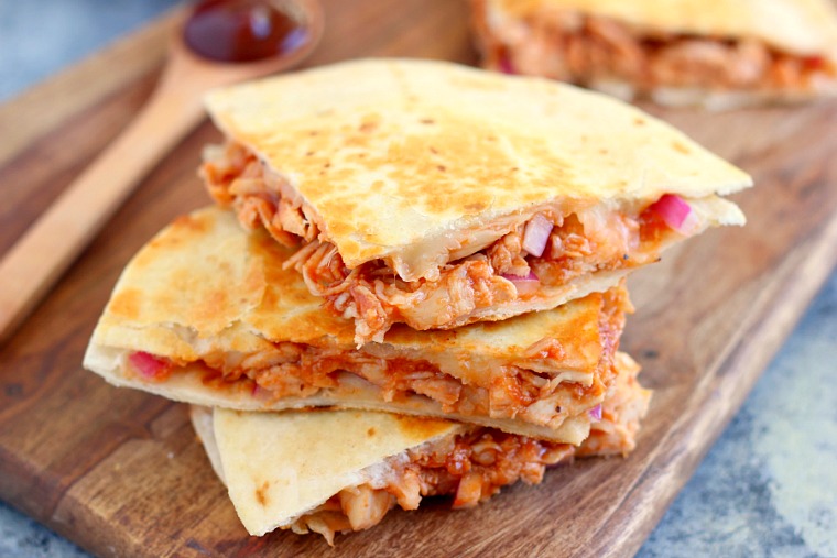 a stack of three pieces of a bbq chicken quesadilla on a wood board 