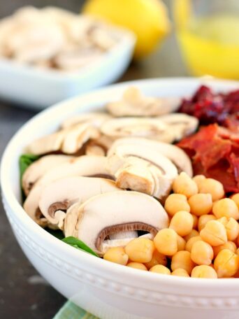 This Cranberry Mushroom Spinach Salad with Lemon Basil Vinaigrette combines baby spinach leaves, dried cranberries, fresh mushrooms, chickpeas, and crumbled bacon, all tossed with a lemon basil dressing. This dish is easy to throw together and serves as the perfect lunch or dinner!