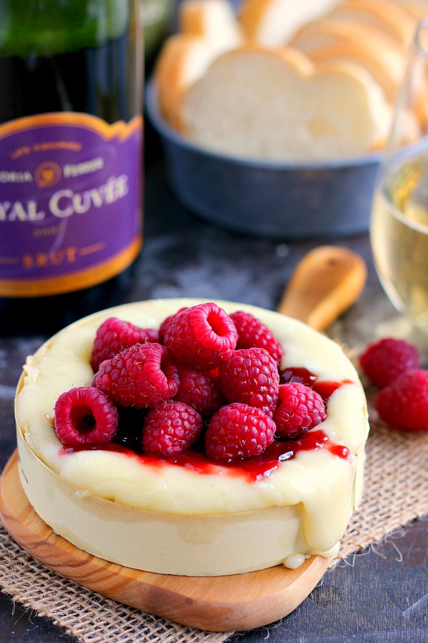 raspberry baked brie on a wood serving board 