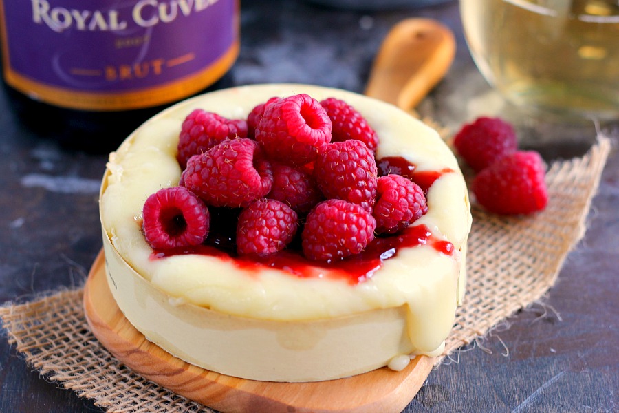 raspberry baked brie appetizer on a wood board 