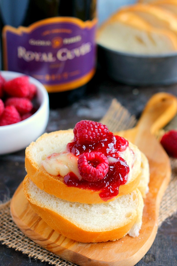Two bread slices topped with melted brie, raspberries, and jam 