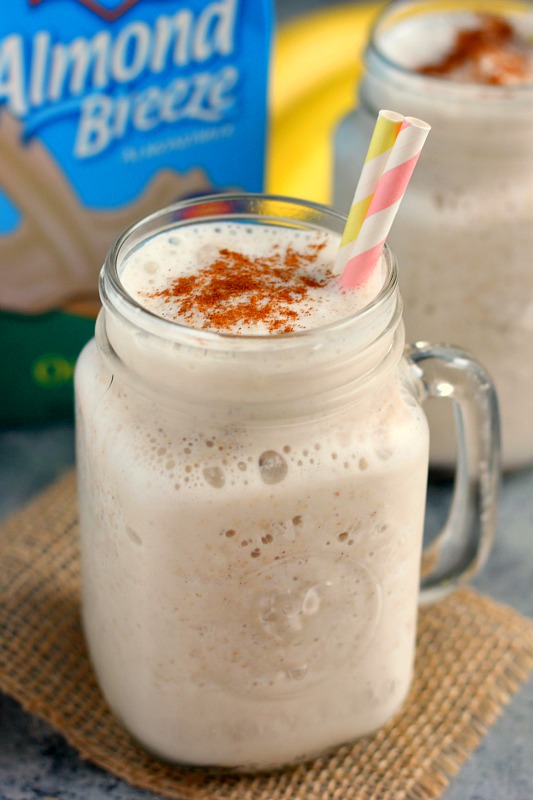 A creamy frozen banana oat smoothie in a glass mason jar, with two striped straws. 