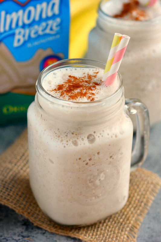 A healthy frozen banana smoothie in a glass mason jar with two striped straws. 