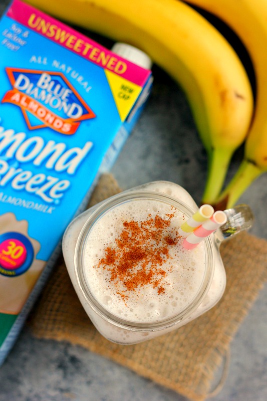 A creamy frozen banana oat smoothie in a glass mason jar, with two striped straws, seen from above. 