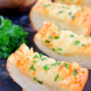 This Cheesy Garlic Bread is packed with buttery spread that's combined with garlic and then topped with Parmesan and mozzarella cheeses. It bakes up crispy and full of flavor. If you're looking for the perfect garlic bread to make, then this is it!