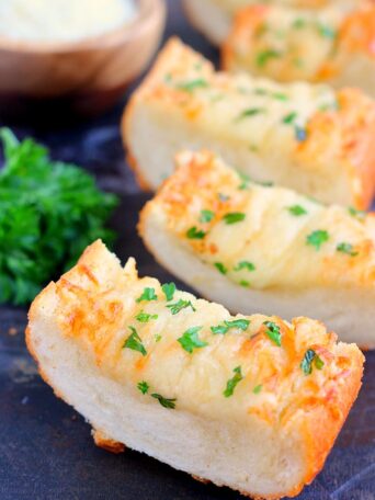 This Cheesy Garlic Bread is packed with buttery spread that's combined with garlic and then topped with Parmesan and mozzarella cheeses. It bakes up crispy and full of flavor. If you're looking for the perfect garlic bread to make, then this is it!