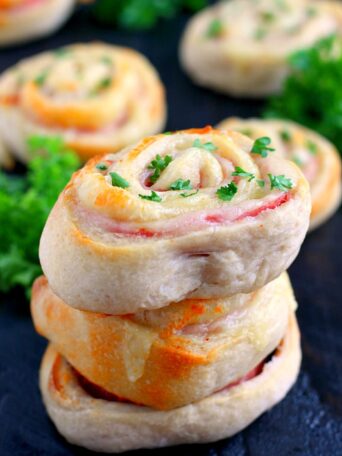 These Baked Ham and Cheese Roll-Ups contain just three ingredients and are ready in less than 20 minutes. Filled with deli ham, swiss cheese, and rolled up in a pre-made pizza dough, these roll-ups are sure to be the hit of the dinner table!