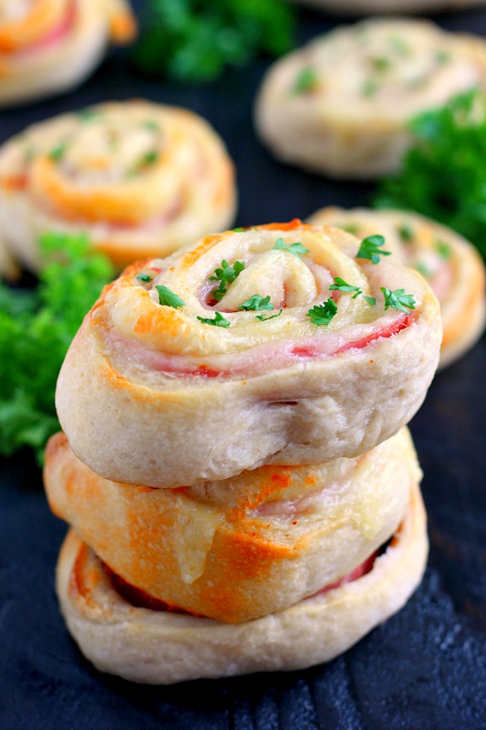 A stack of three baked ham and cheese roll ups.