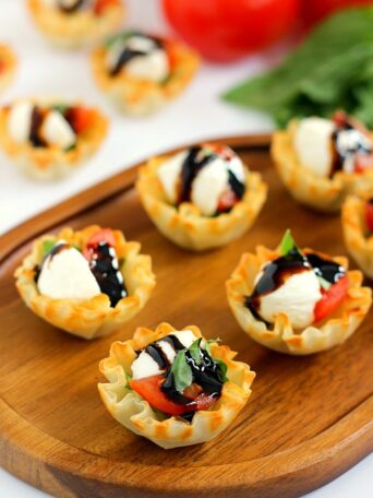 These Caprese Cups are a delicious bite-sized appetizer that will be the hit of your next party! Filled with cherry tomatoes, mozzarella cheese, fresh basil and a drizzle of balsamic glaze, these bites are easy to make and even better to eat!
