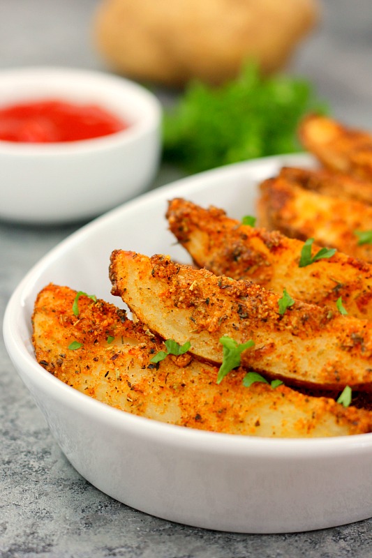 baked garlic parmesan potato wedges in a white bowl