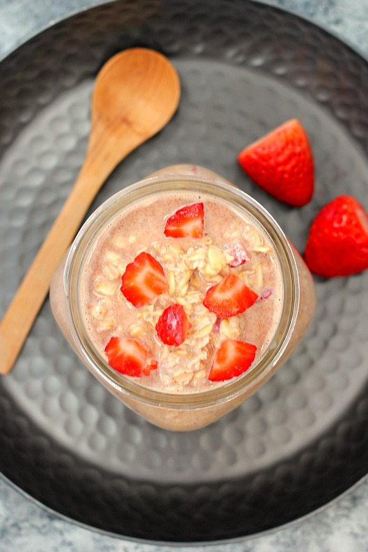 Overhead view of a jar of Nutella overnight oats with strawberries on the side. 