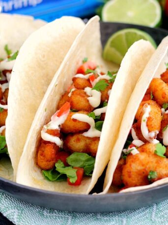 These Cilantro Lime Popcorn Shrimp Tacos are filled with crispy popcorn shrimp, a zesty cilantro lime sauce, and topped with a cilantro cream drizzle. Easy to make and ready in just 20 minutes, this flavorful dish will be the hit of your dinner table!