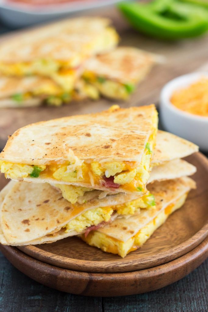 breakfast quesadilla slices on a stack of two wooden plates. 