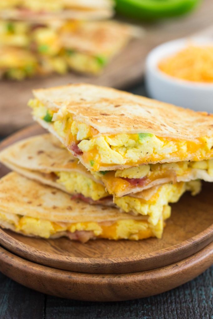 Three slices of breakfast quesadillas on wooden plates. 