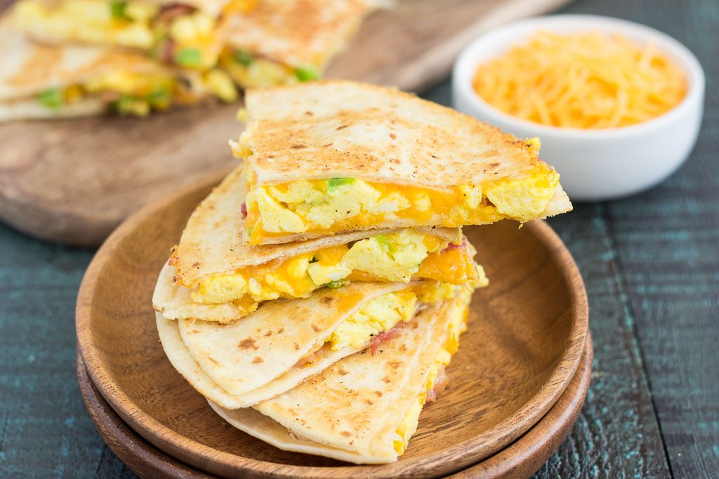 Four breakfast quesadilla slices on wooden plates. 