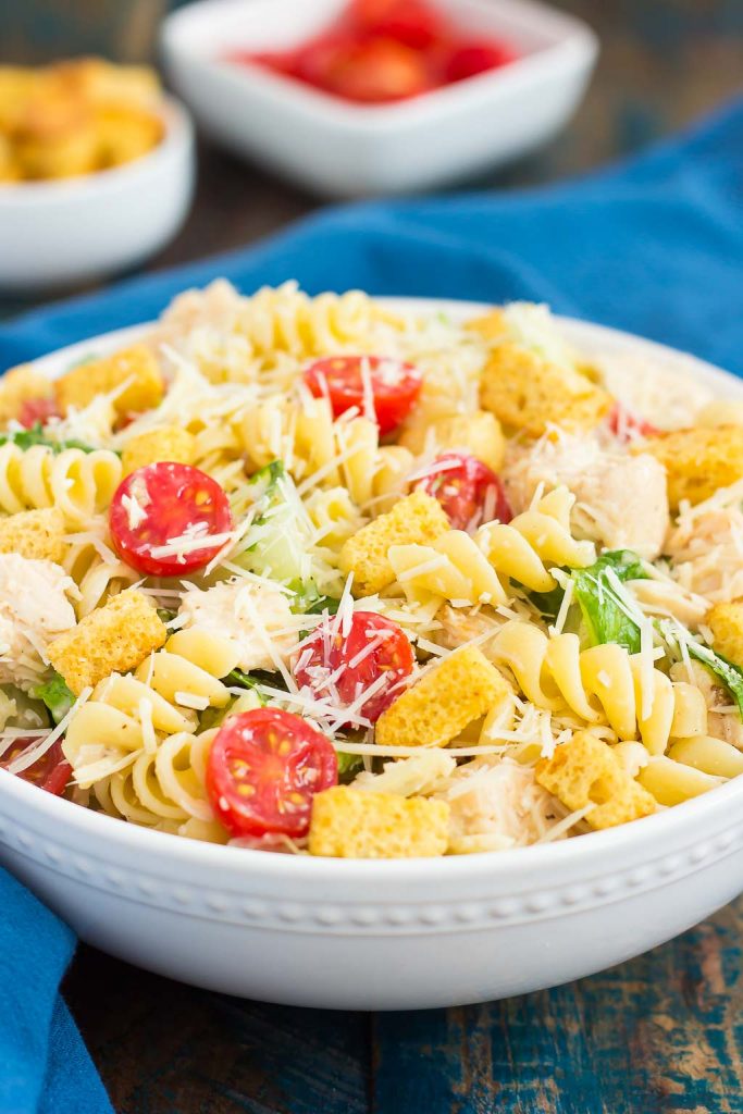 large bowl of chicken caesar pasta salad garnished with parmesan 