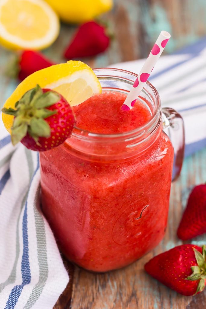 blended strawberry lemonade in mason jar garnished with lemon wedge and fresh strawberry