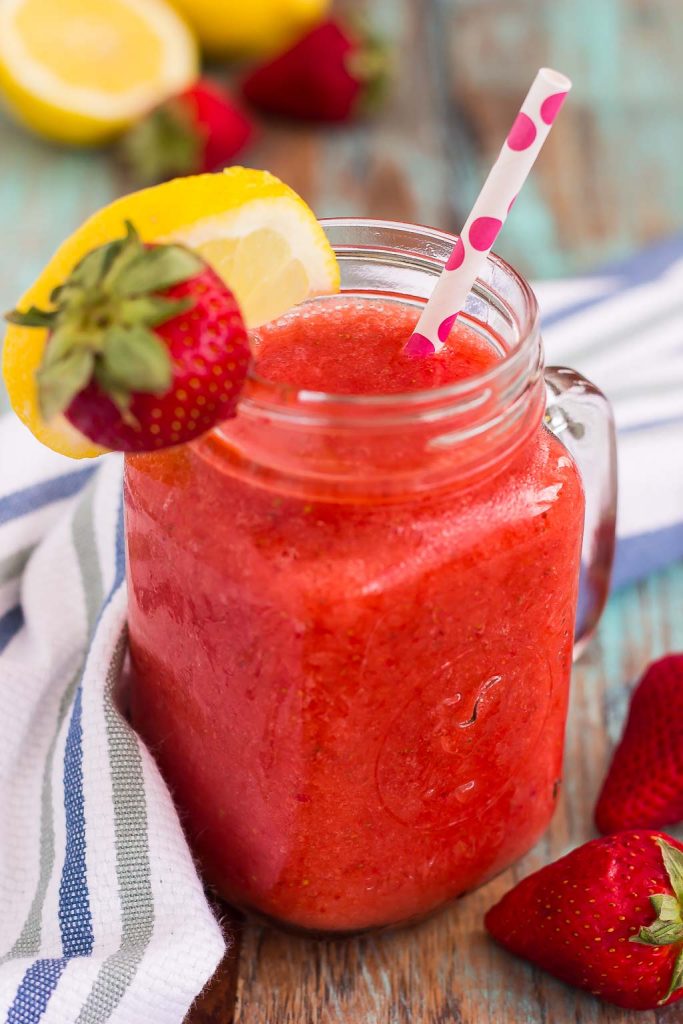 frozen strawberry lemonade in mason jar garnished with lemon wedge and fresh strawberry