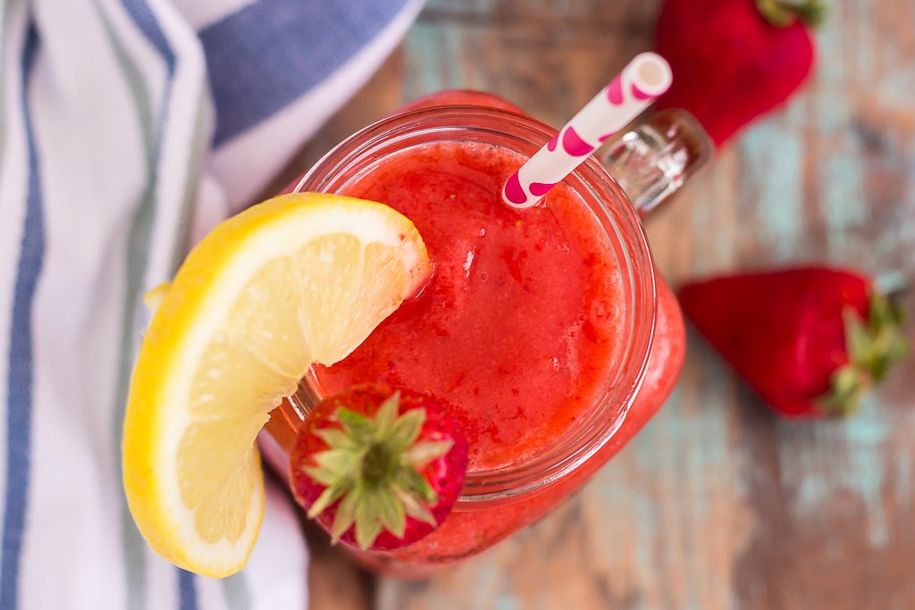 overhead view of blended strawberry lemonade in mason jar garnished with lemon wedge and fresh strawberry