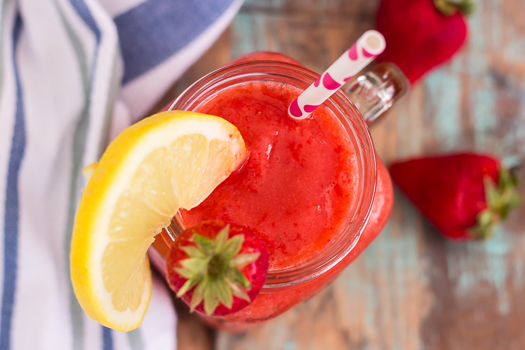 overhead view of blended strawberry lemonade in mason jar garnished with lemon wedge and fresh strawberry