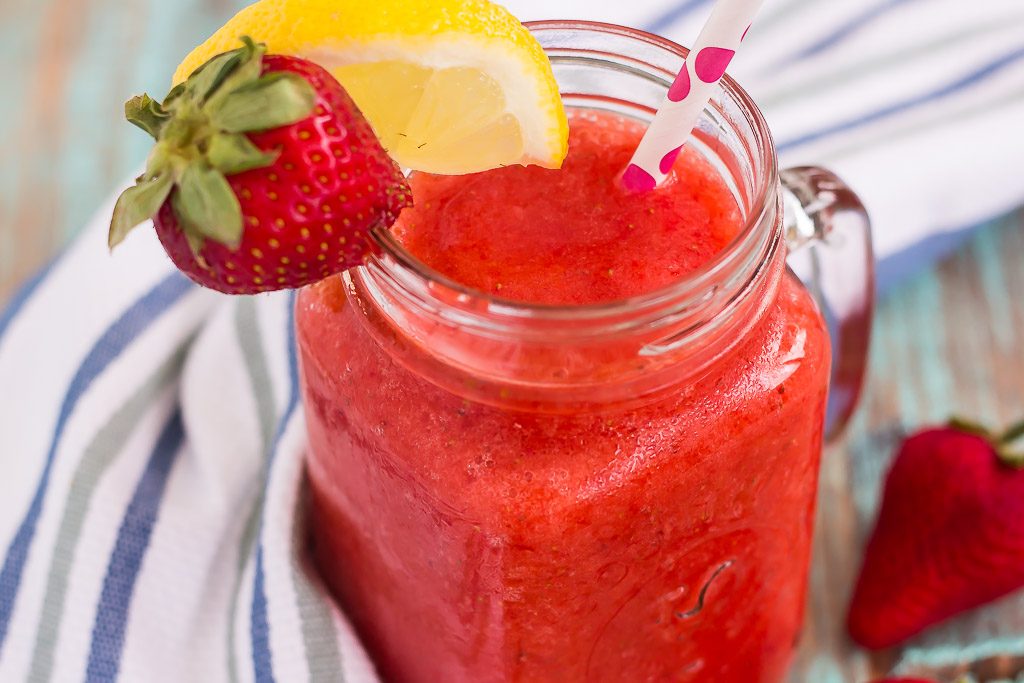 frozen strawberry lemonade in mason jar garnished with lemon wedge and fresh strawberry