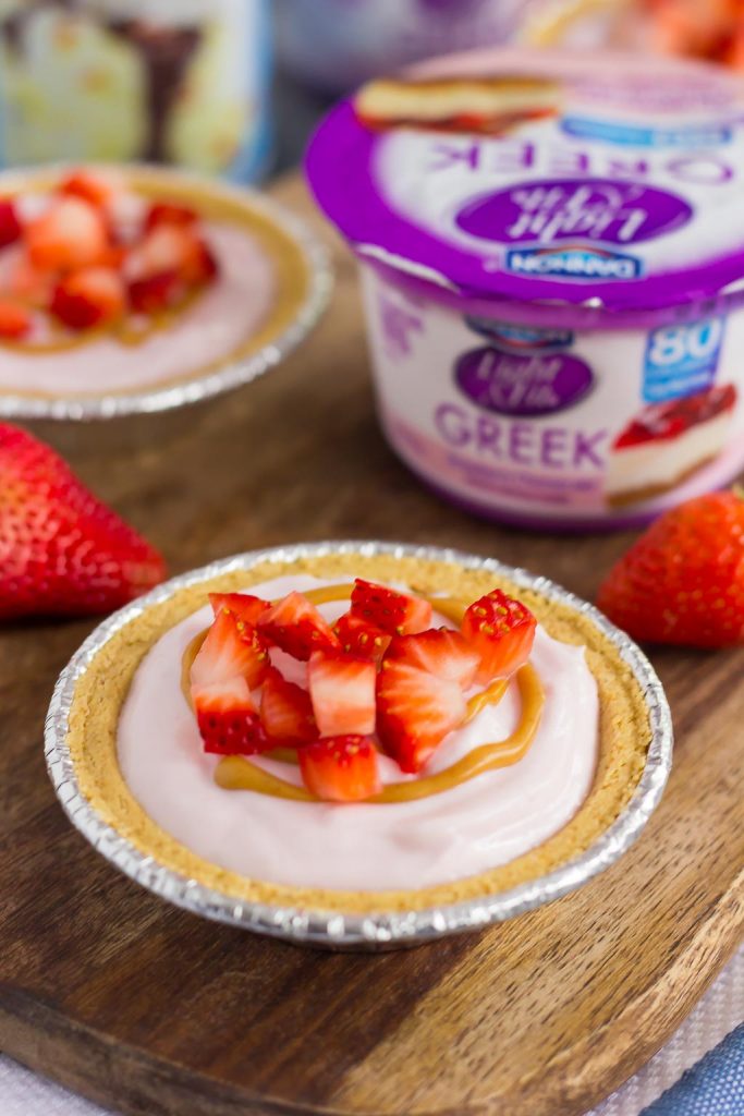 These Mini Strawberry Peanut Butter Cheesecake Pies are filled with Dannon® Light & Fit® Strawberry Cheesecake Greek Yogurt, creamy peanut butter, and fresh strawberries. Easy to make and packed with flavor, you can enjoy this no-bake, simple dessert that's perfect for the warmer weather!