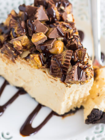 This No-Bake Peanut Butter Cup Cheesecake starts with an Oreo peanut butter cookie crust, followed by a creamy, peanut butter batter, and sprinkled with chopped peanut butter cups and chocolate syrup. It's an easy dessert that takes just minutes to prepare and is packed with flavor!