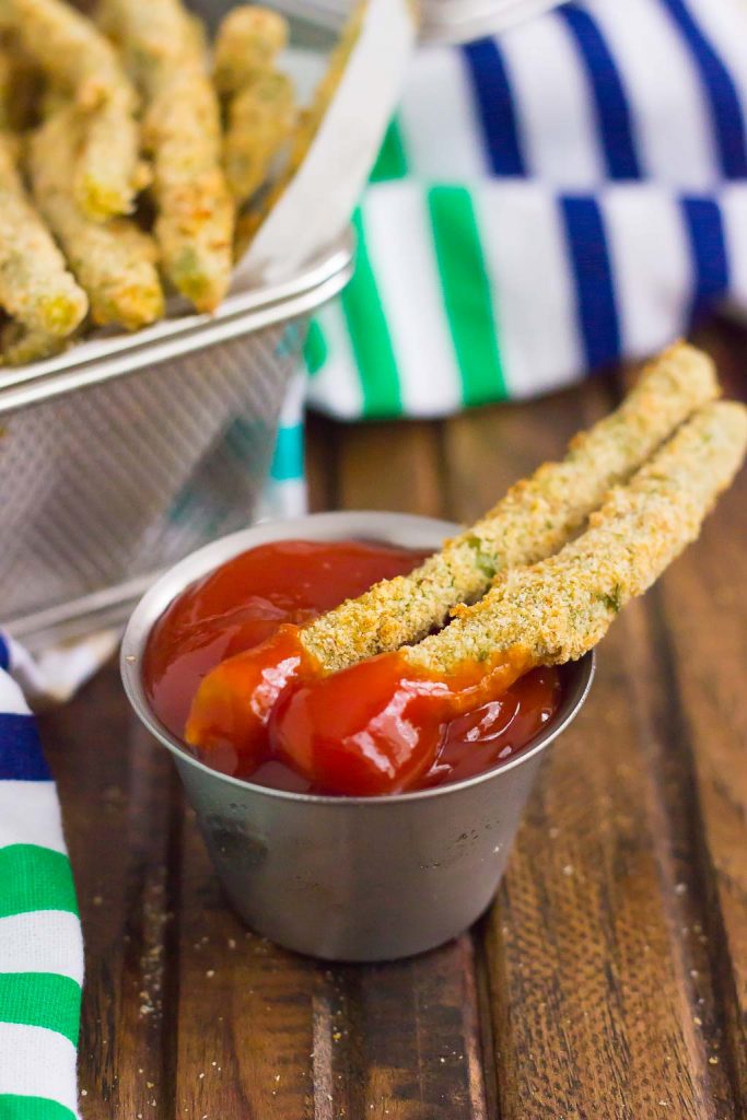 two baked green bean fries dunked in ketchup