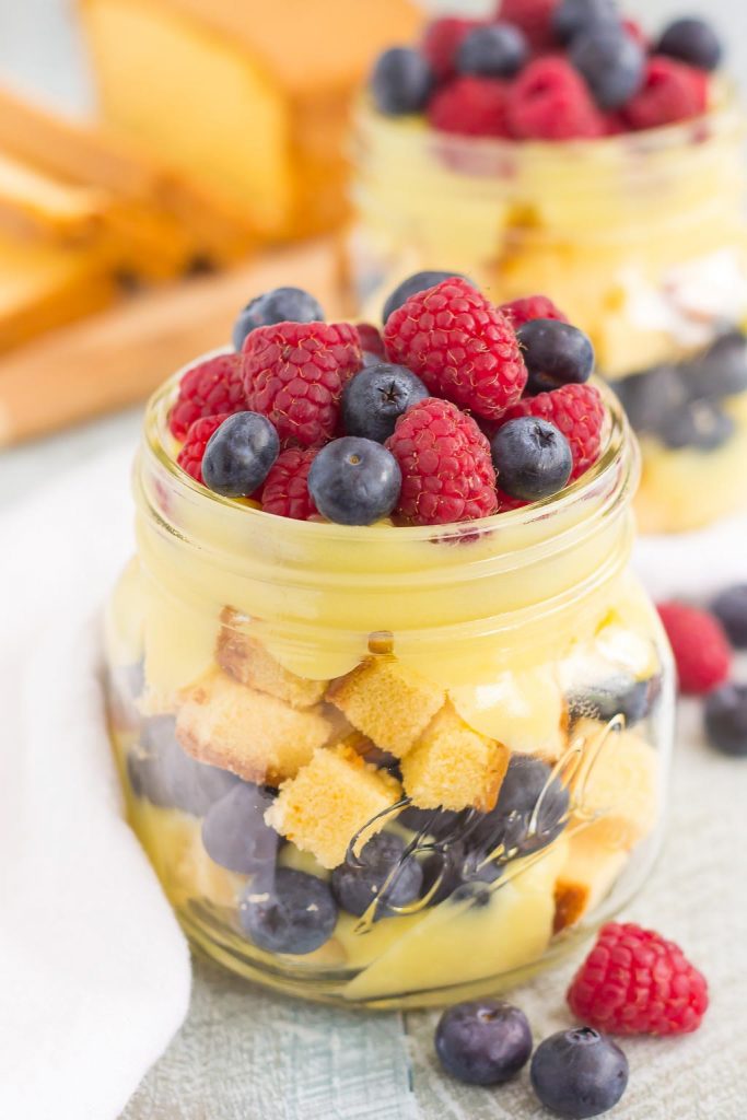 Two pound cake trifles in glass jars, next to a sliced loaf of pound cake. 