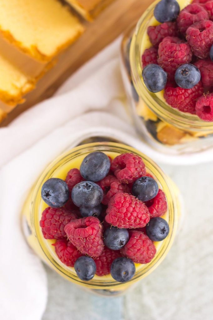 Overhead view of two summer berry trifles in glass jars. 
