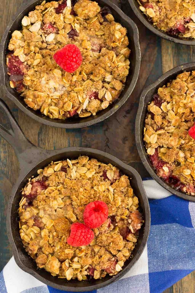 Overhead view of three mini cast iron skillets of raspberry rhubarb crisp. 