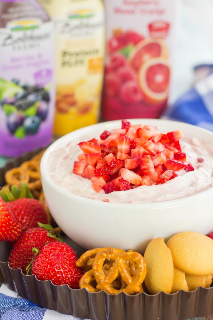A bowl of strawberry cheesecake fruit dip, surrounded by dipper options. 