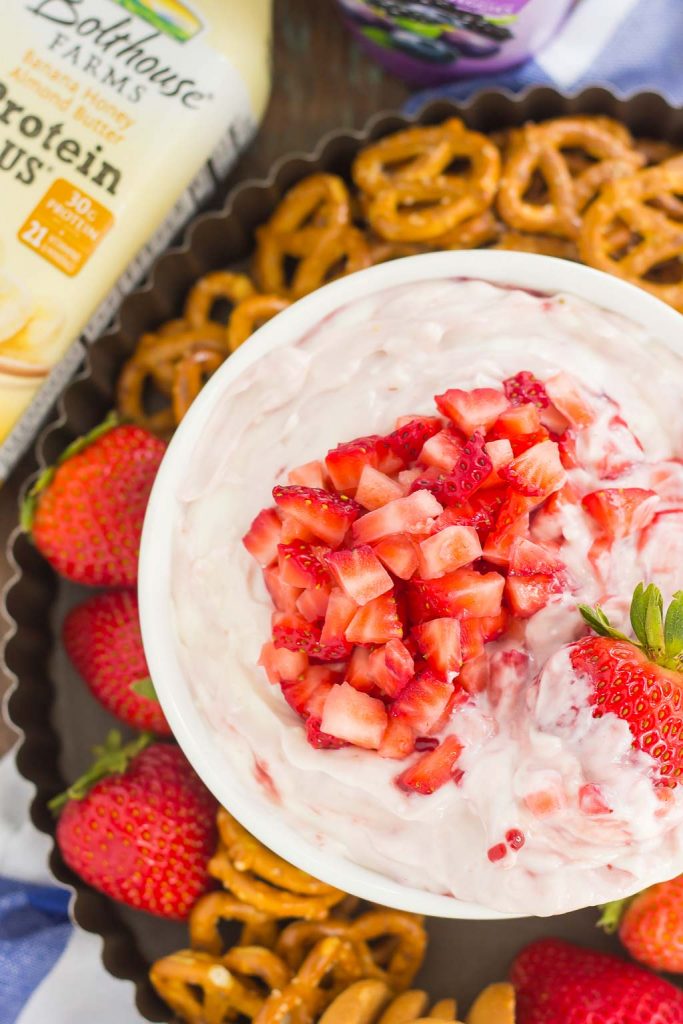 Overhead view of a bowl of strawberry cream cheese dip, surrounded by various dippers. 
